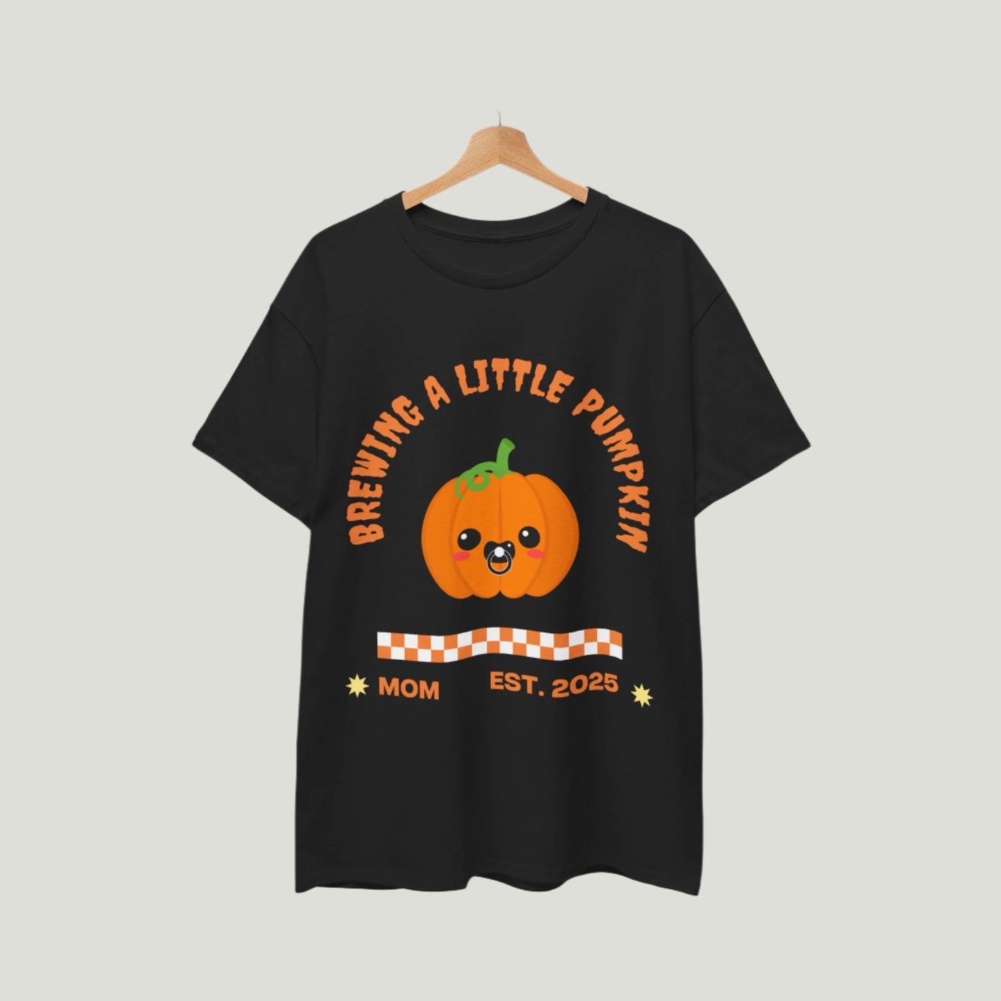  Brewing A Little Pumpkin T-Shirt in black color featuring an adorable pumpkin with a pacifier and the text "Brewing a Little Pumpkin, Mom Established 2025." This charming and comfortable tee is perfect for announcing a pregnancy during Halloween, making it a delightful choice for expecting parents. Ideal for festive celebrations, family gatherings, and capturing memorable photos!