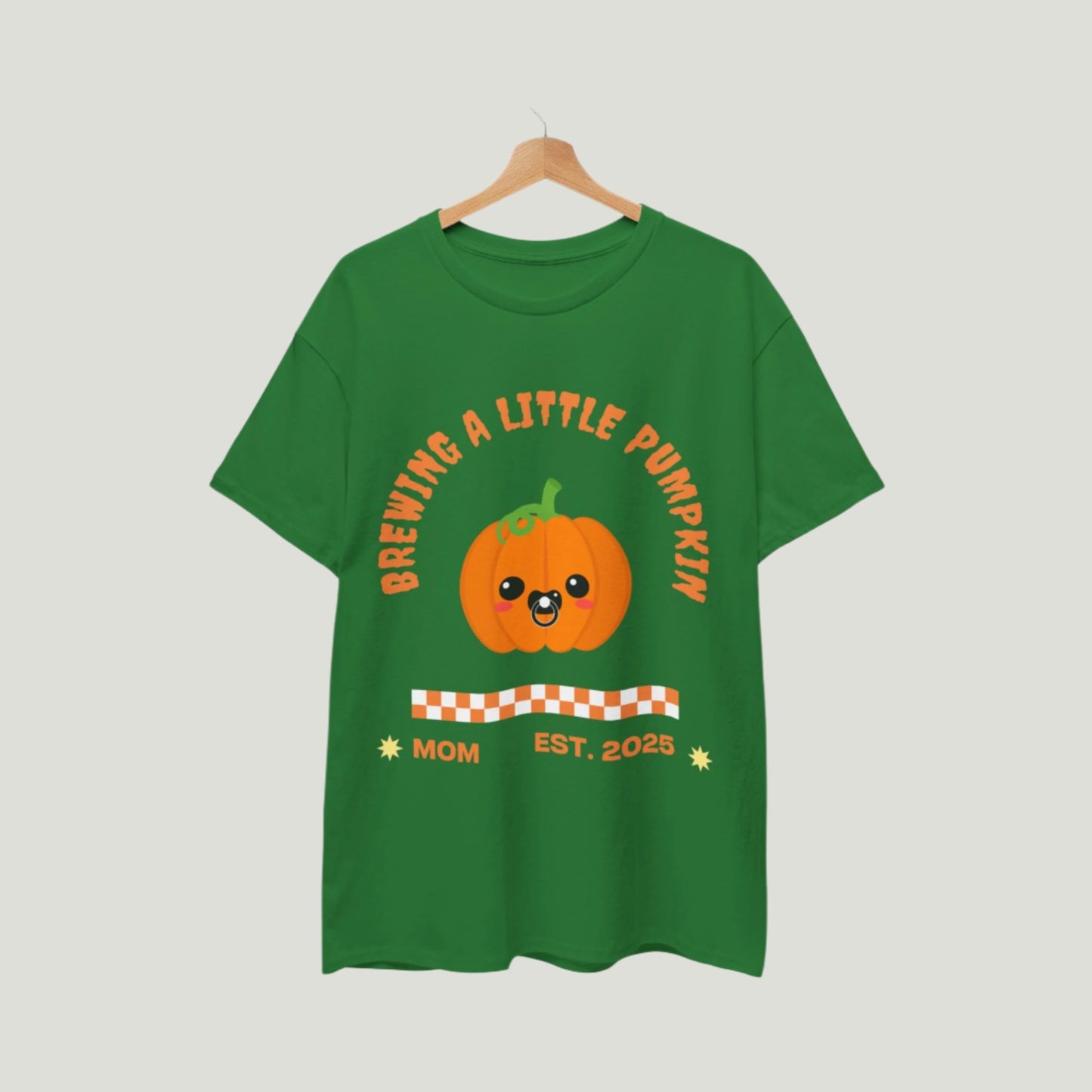 Turf Green Brewing A Little Pumpkin T-Shirt featuring an adorable pumpkin with a pacifier and the text "Brewing a Little Pumpkin, Mom Established 2025." This charming and comfortable tee is perfect for announcing a pregnancy during Halloween, making it a delightful choice for expecting parents. Ideal for festive celebrations, family gatherings, and capturing memorable photos!