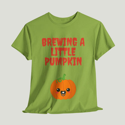 Kiwi colored t-shirt featuring red text "Brewing A Little Pumpkin," perfect for announcing a pregnancy during Halloween, worn by a smiling woman.