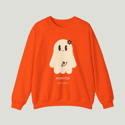 Cute Ghost Momster Sweatshirt in orange color featuring an adorable illustration of a ghost with a skeleton holding a pacifier, waving from the belly. The design includes the text “Momster. Established 2025,” making it an ideal choice for announcing a pregnancy during Halloween celebrations. Perfect for a fun and festive reveal!