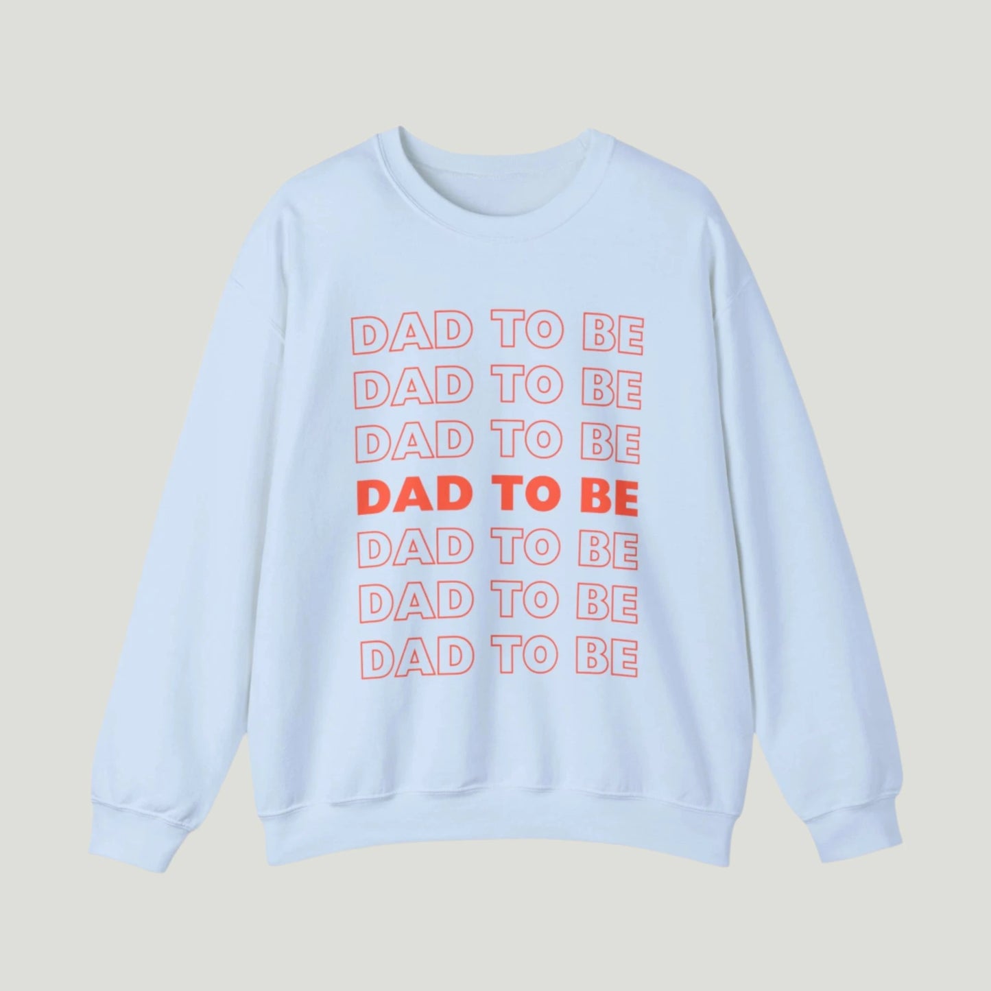 Light Blue Dad To Be Sweatshirt featuring bold orange lettering with the phrase "Dad To Be" repeated multiple times. Ideal for announcing pregnancy to expectant fathers in a fun and stylish way. Perfect for celebrating this exciting journey!